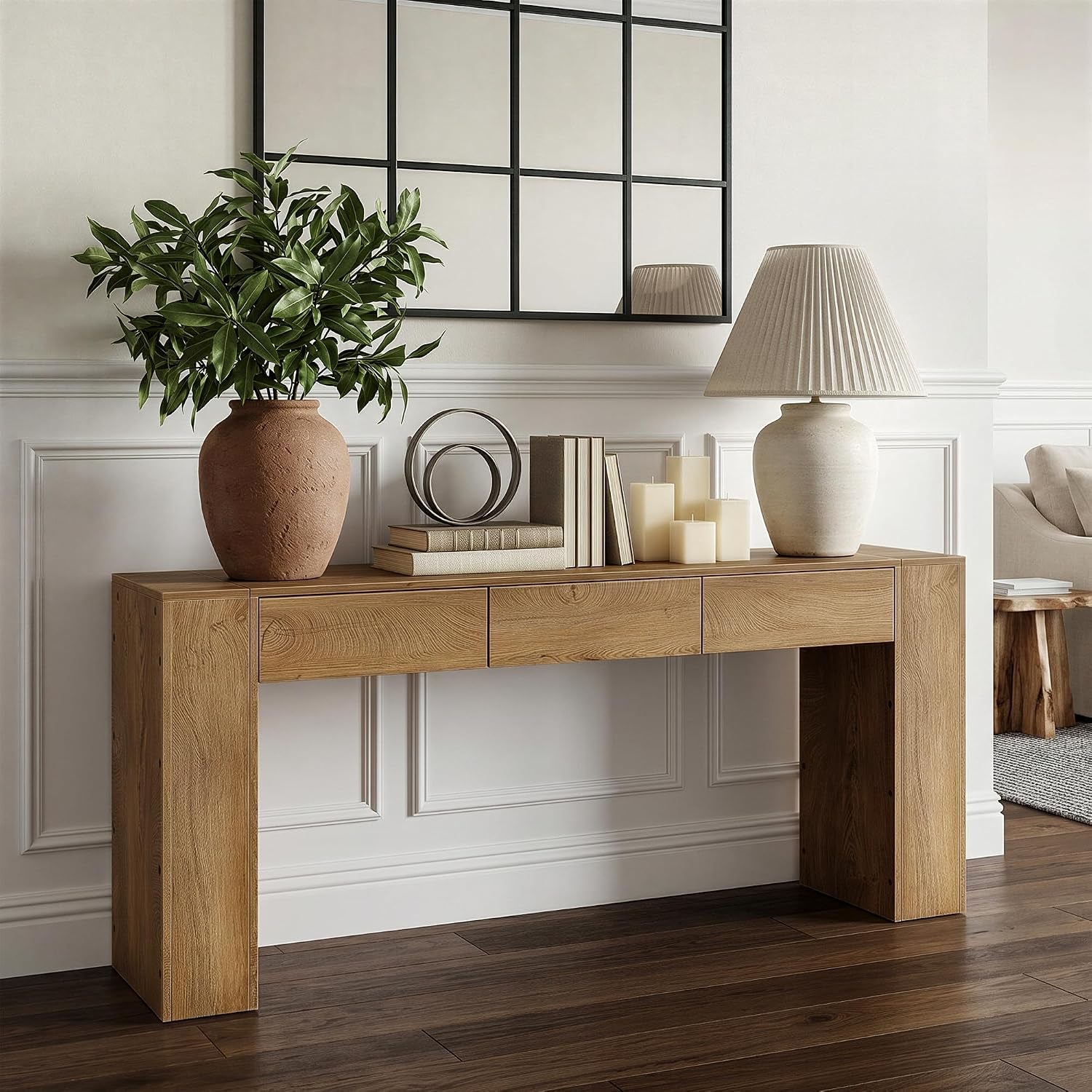 Close side view of the console’s front and left leg showing the three drawer fronts and tabletop styling of books and