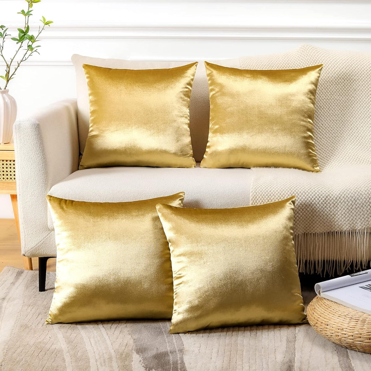 Two square gold velvet pillow covers on a cream sofa with two rectangular gold pillows on the floor