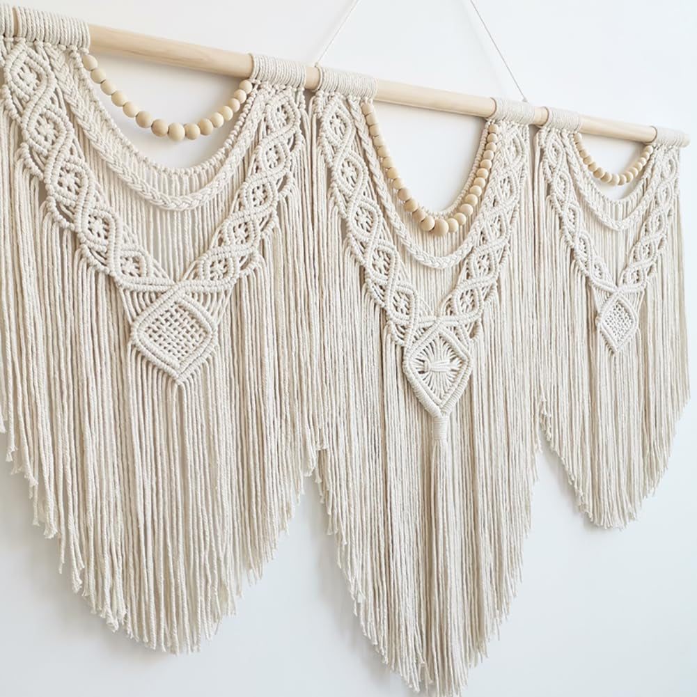 Angled view of ivory macrame panels and fringe on a wooden rod