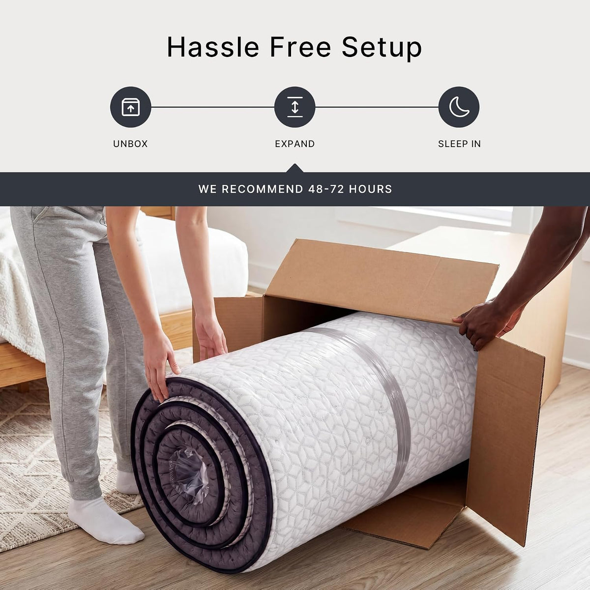 Compressed rolled mattress being removed from a cardboard box on a bedroom floor to demonstrate unboxing and setup