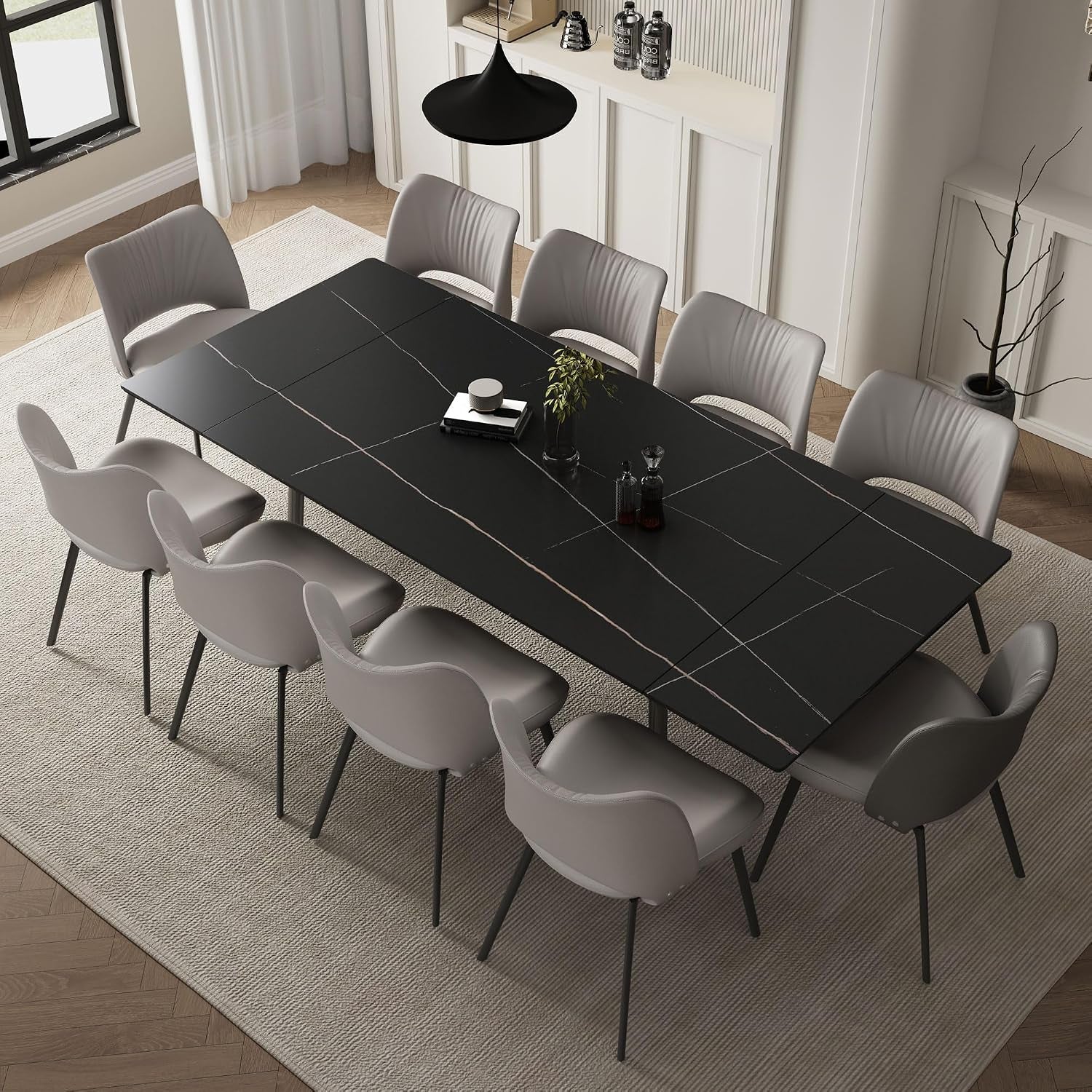 Modern black rectangular dining table fully extended with eight gray chairs arranged around it in a bright dining room.