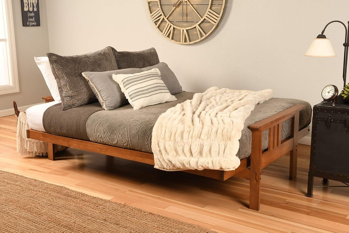 Full-size futon converted to a bed with medium wood frame and gray bedding in a staged bedroom setting