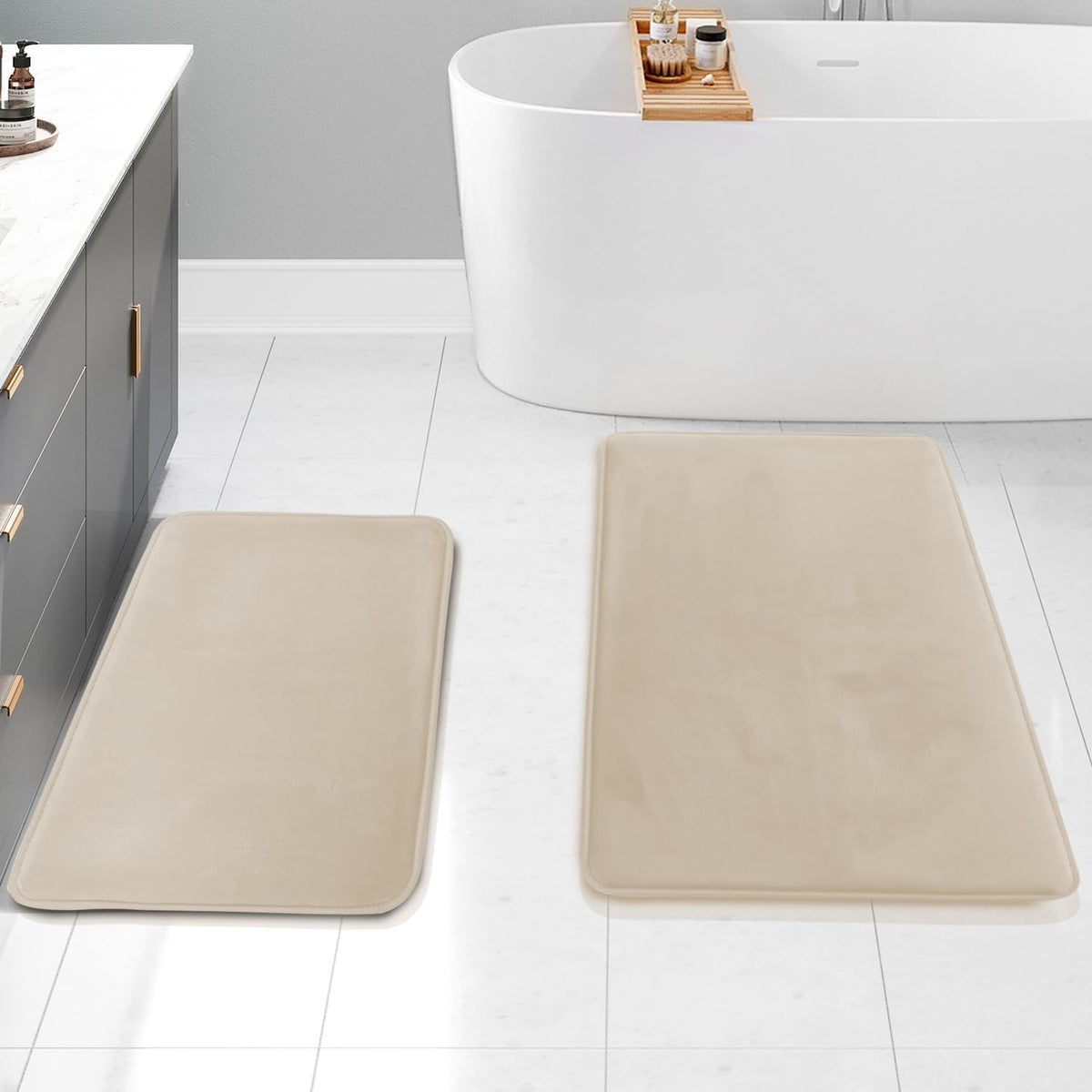 Beige rectangular mats on white tile in front of a freestanding bathtub with a wooden bath tray across the tub.