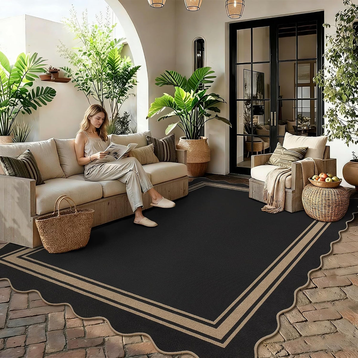 Black scalloped rug with double tan border under a sofa and armchair in a bright indoor seating area.