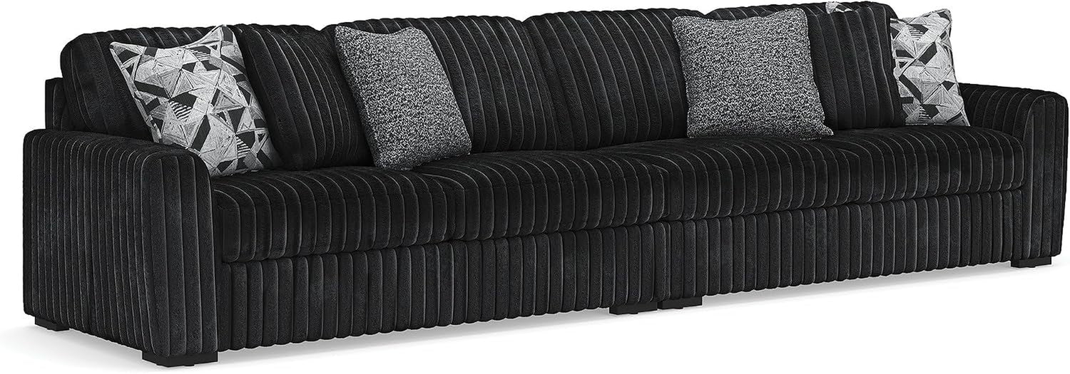 Straight-on view of a long ribbed sofa with low arms and four decorative pillows.