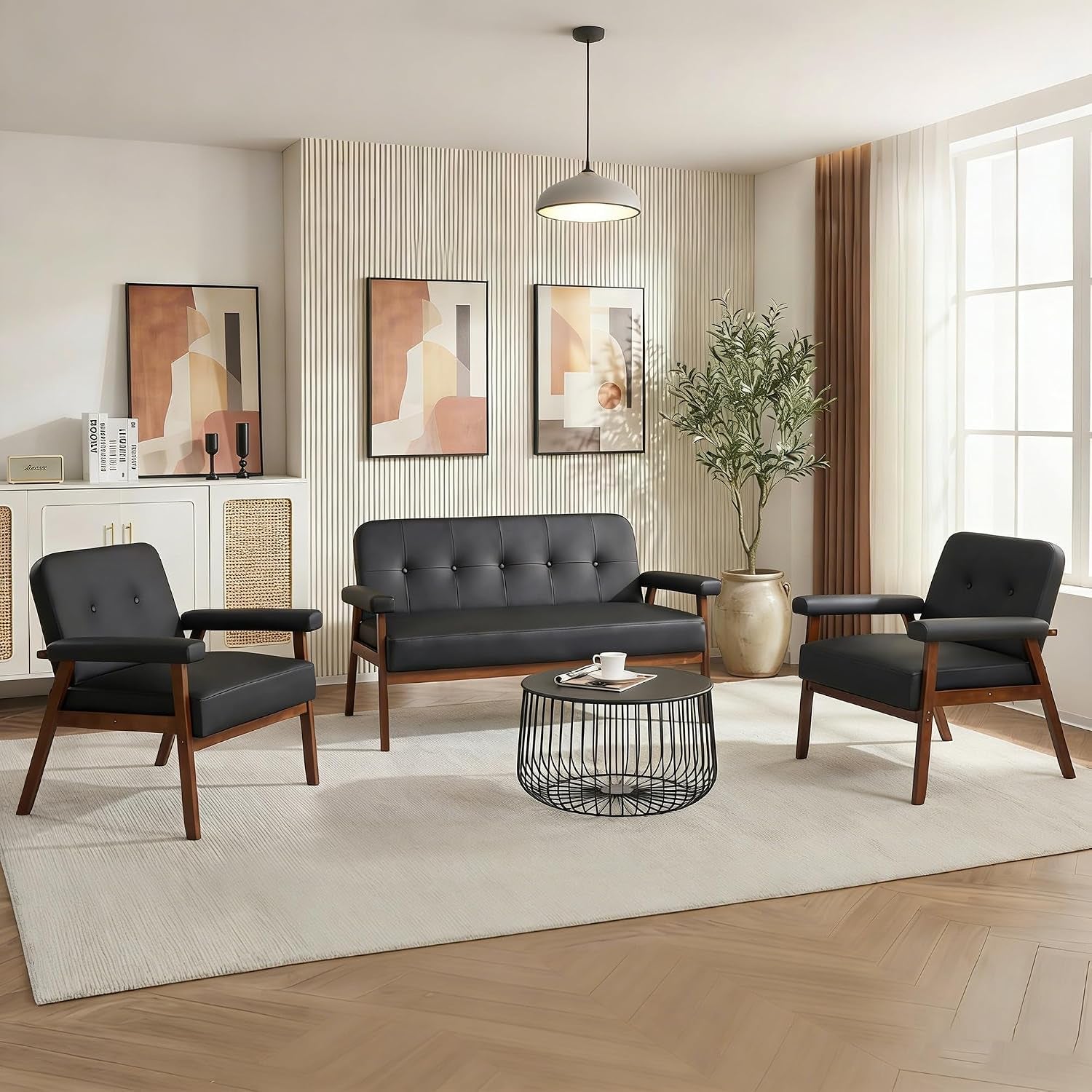 Styled living room with the black faux leather loveseat centered between two matching armchairs and a round wire coffee