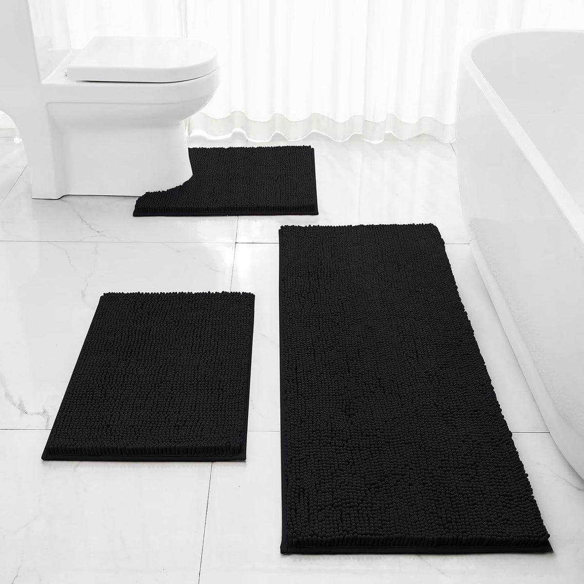 Three dark grey chenille bath rugs on a white tiled bathroom floor, including U-shaped, small rectangle, and long runner.