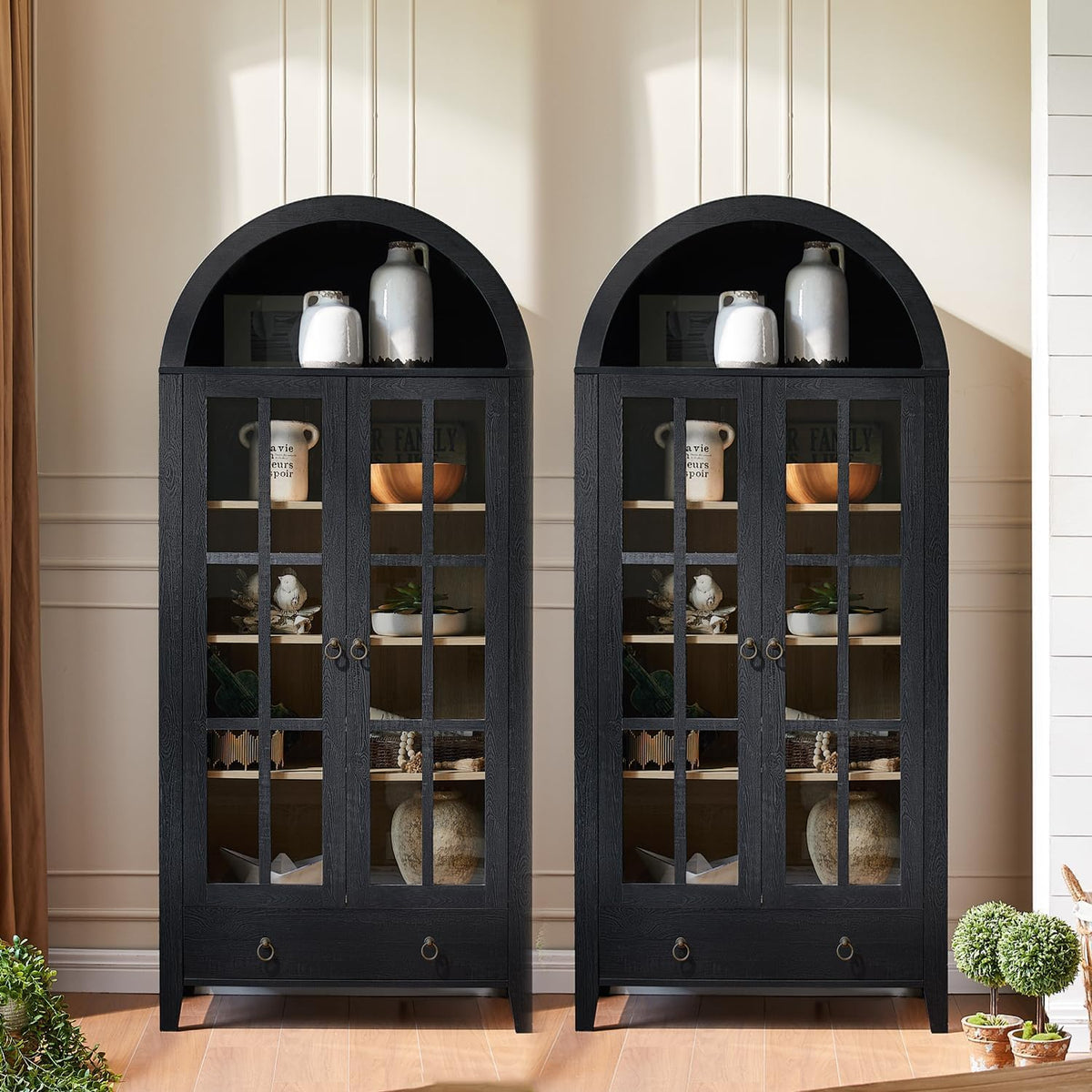 Two black arched cabinets shown side-by-side, each filled with decorative bowls and vases.