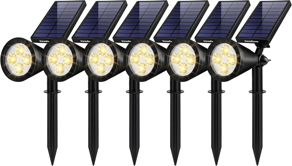 Group of six black solar spotlights with rectangular panels and warm LEDs, shown with ground stakes.