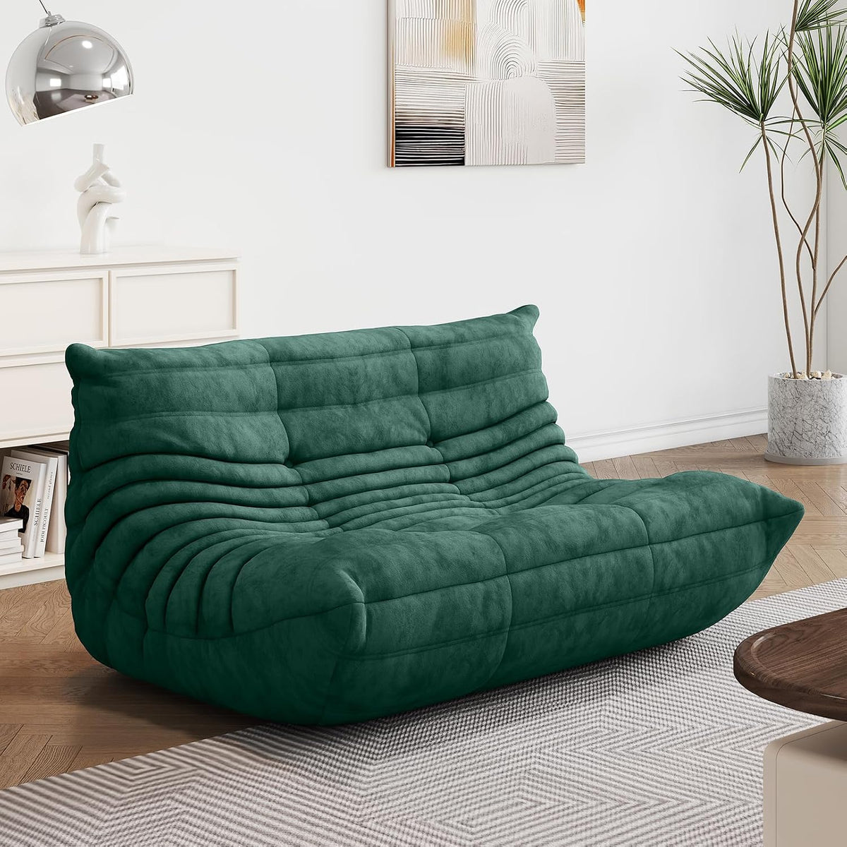Deep green two-seat lounge sofa shown in a bright room with a floor plant and wall art.