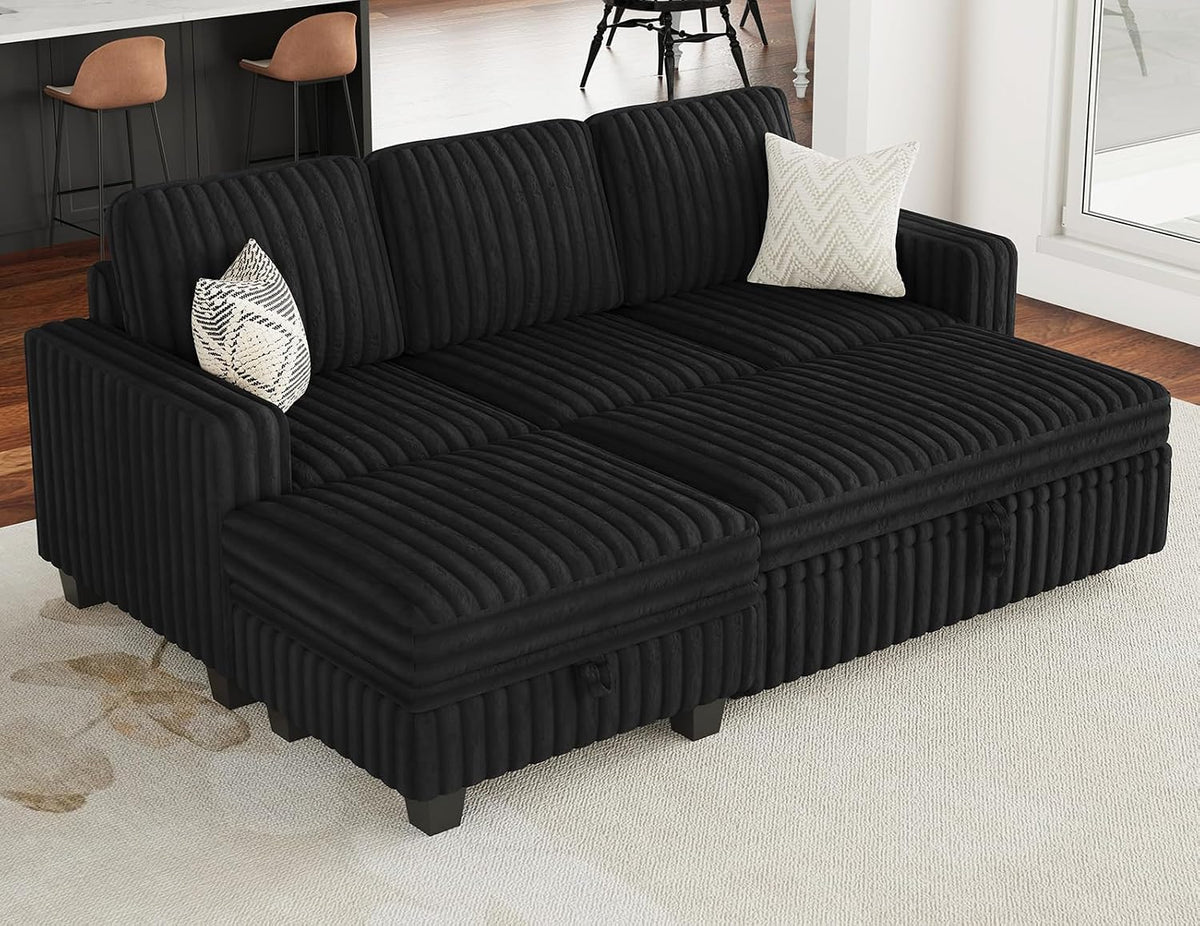 Black corduroy sofa shown low to the ground with two patterned throw pillows and wood flooring