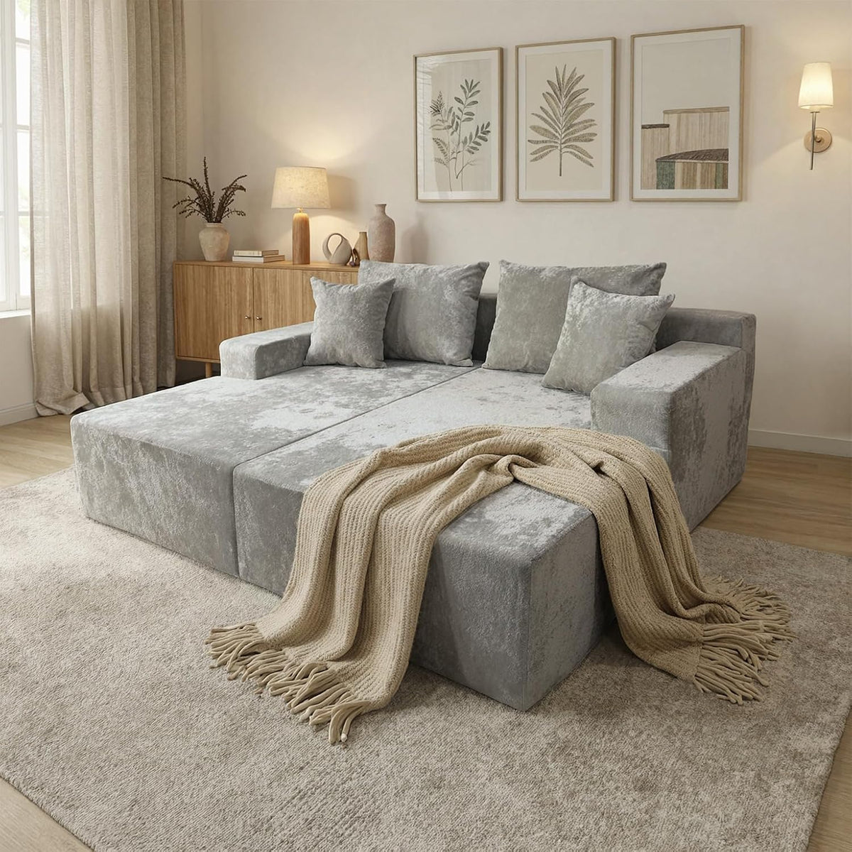 Corner view of a light-gray chaise lounge flattened into a low bed with four matching pillows and a beige knit throw.