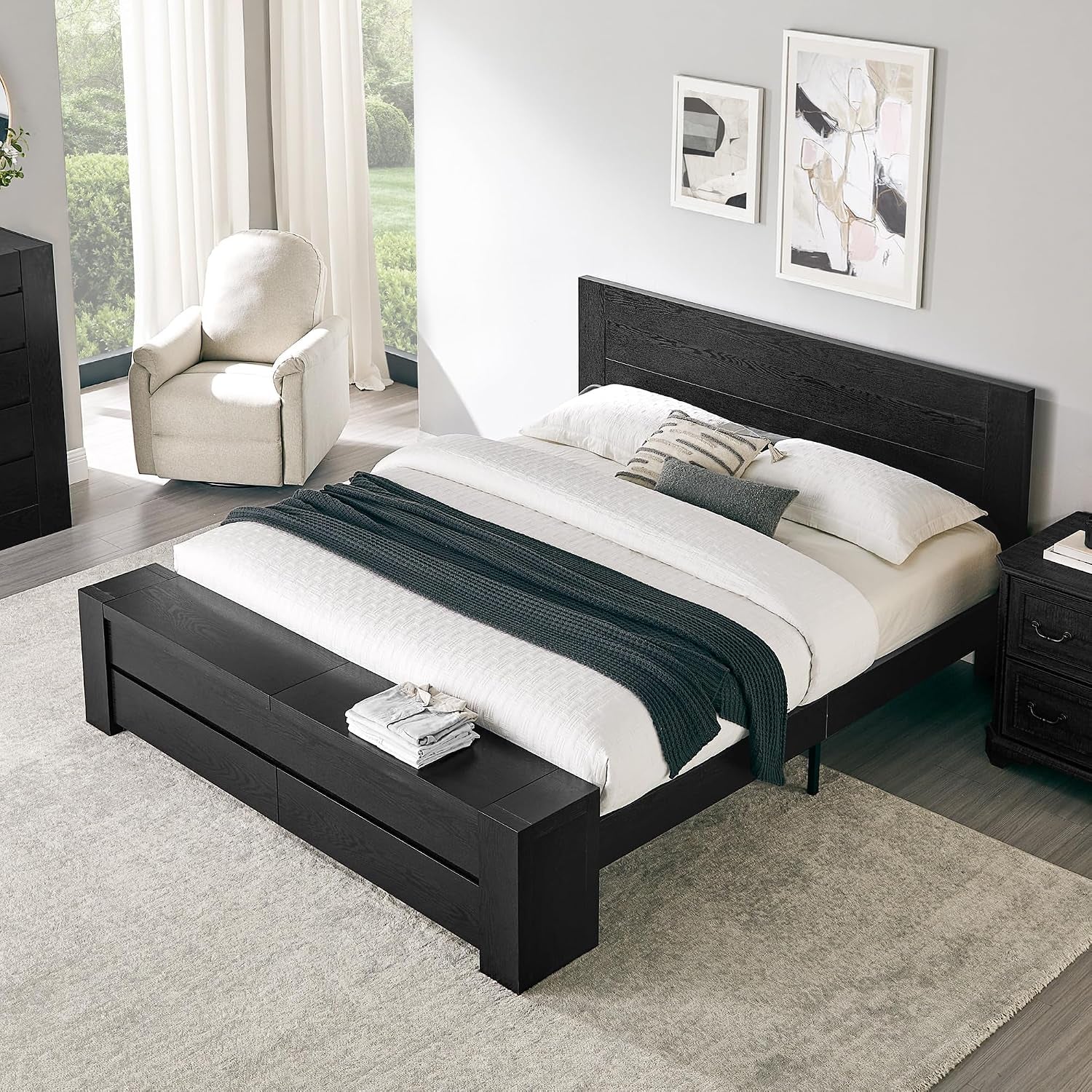 Angled overhead view of a black platform bed with matching storage bench at the foot in a bright room.
