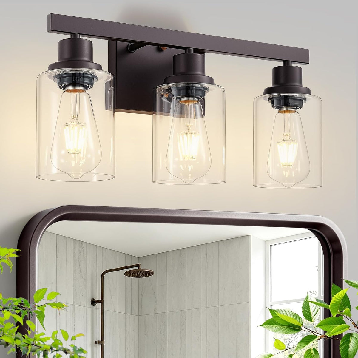 Three-light vanity fixture in a dark finish with clear glass shades above a mirror