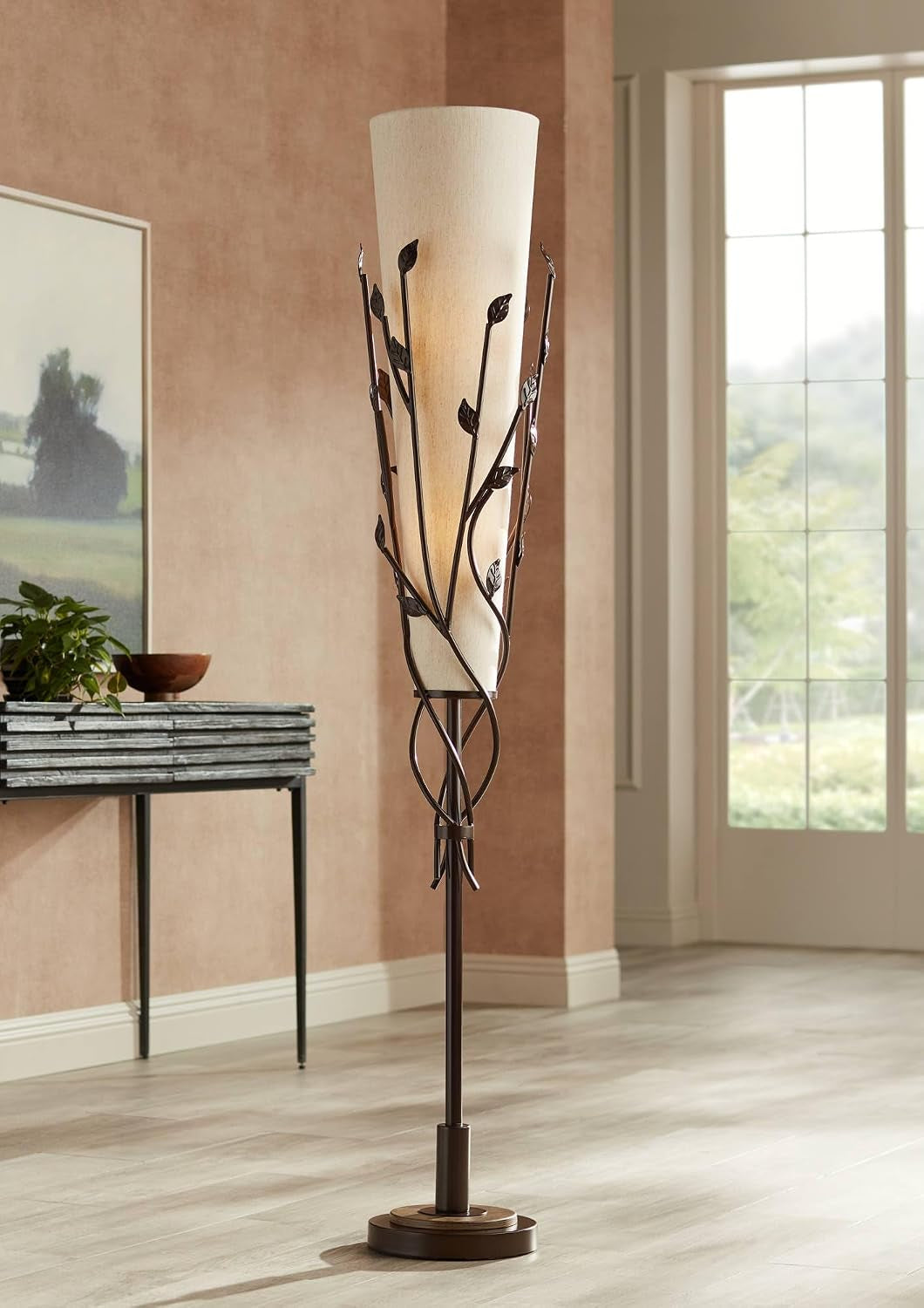 Lit tall floor lamp standing beside a slim console table and window, casting warm uplight on plaster walls