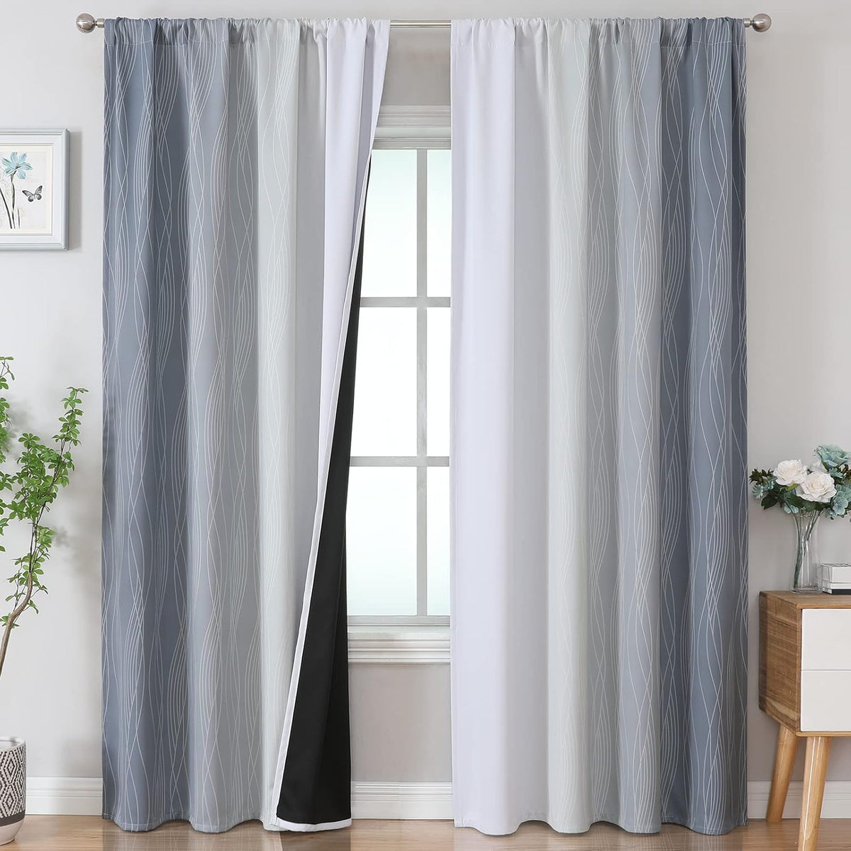 Window with two grey-to-white ombre patterned curtain panels hung on a rod, one pulled back showing black lining.