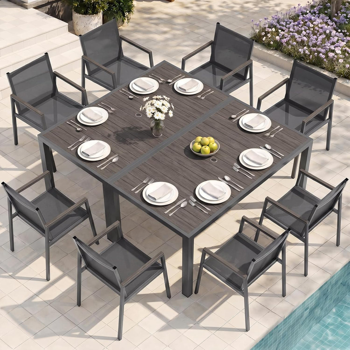 Overhead view of two dark wood-top tables joined, set with plates and eight mesh-seated chairs.