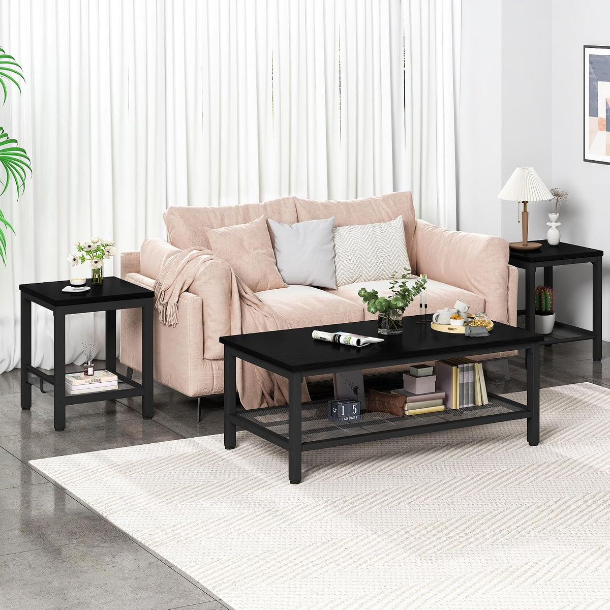 Living room scene with a pale pink sofa flanked by two black end tables and a matching black coffee table on a light rug.