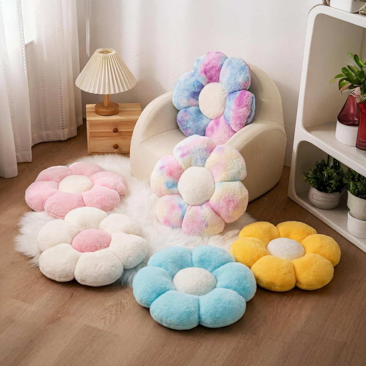 Several flower-shaped plush pillows in pastel colors arranged on a rug and chair