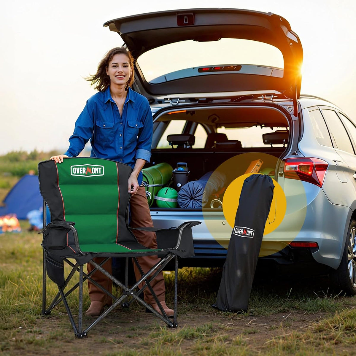 Person setting up a green padded camping chair next to an open car trunk at sunset