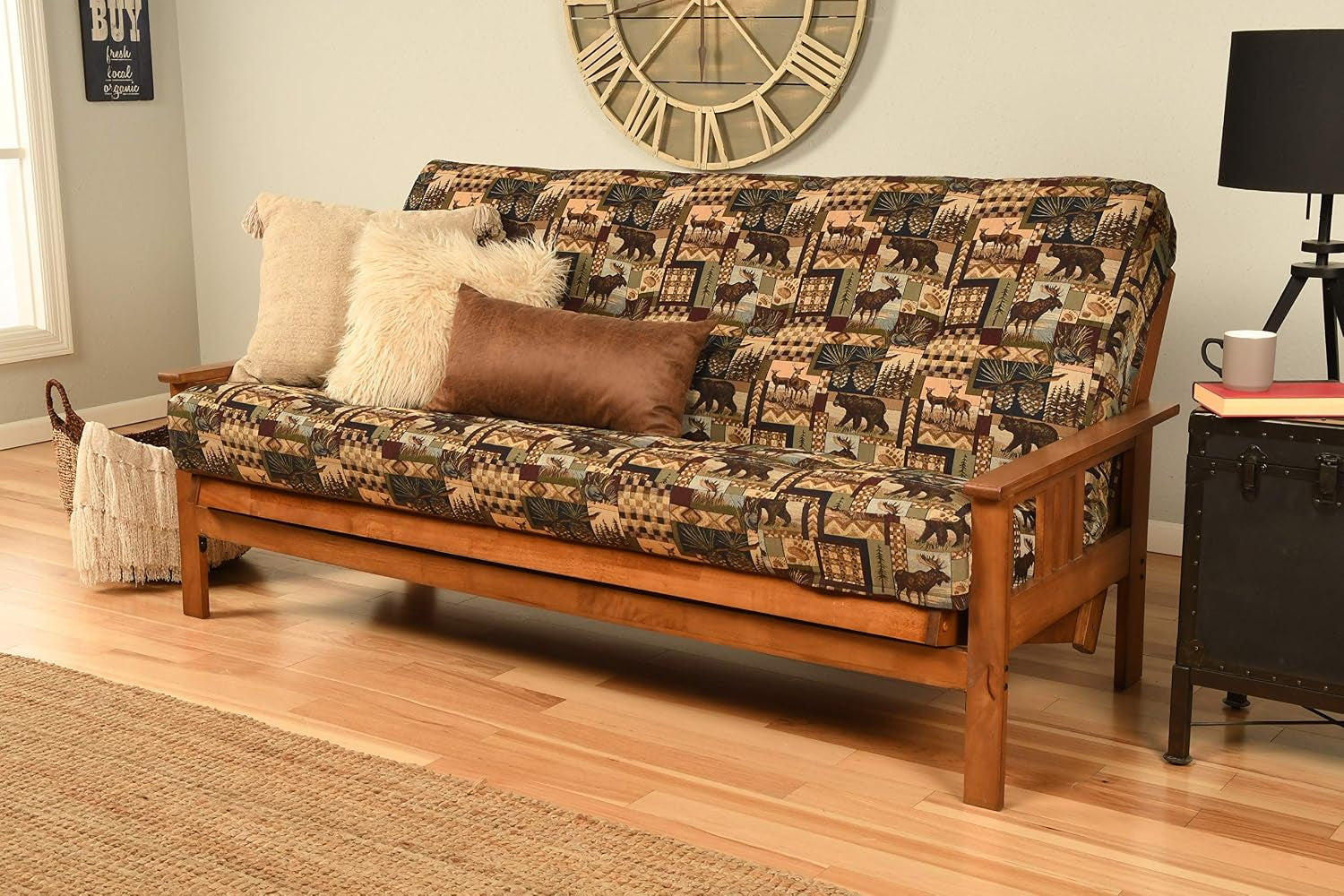 Full futon in living room with multicolored patchwork cover and three assorted decorative pillows on the wooden frame.
