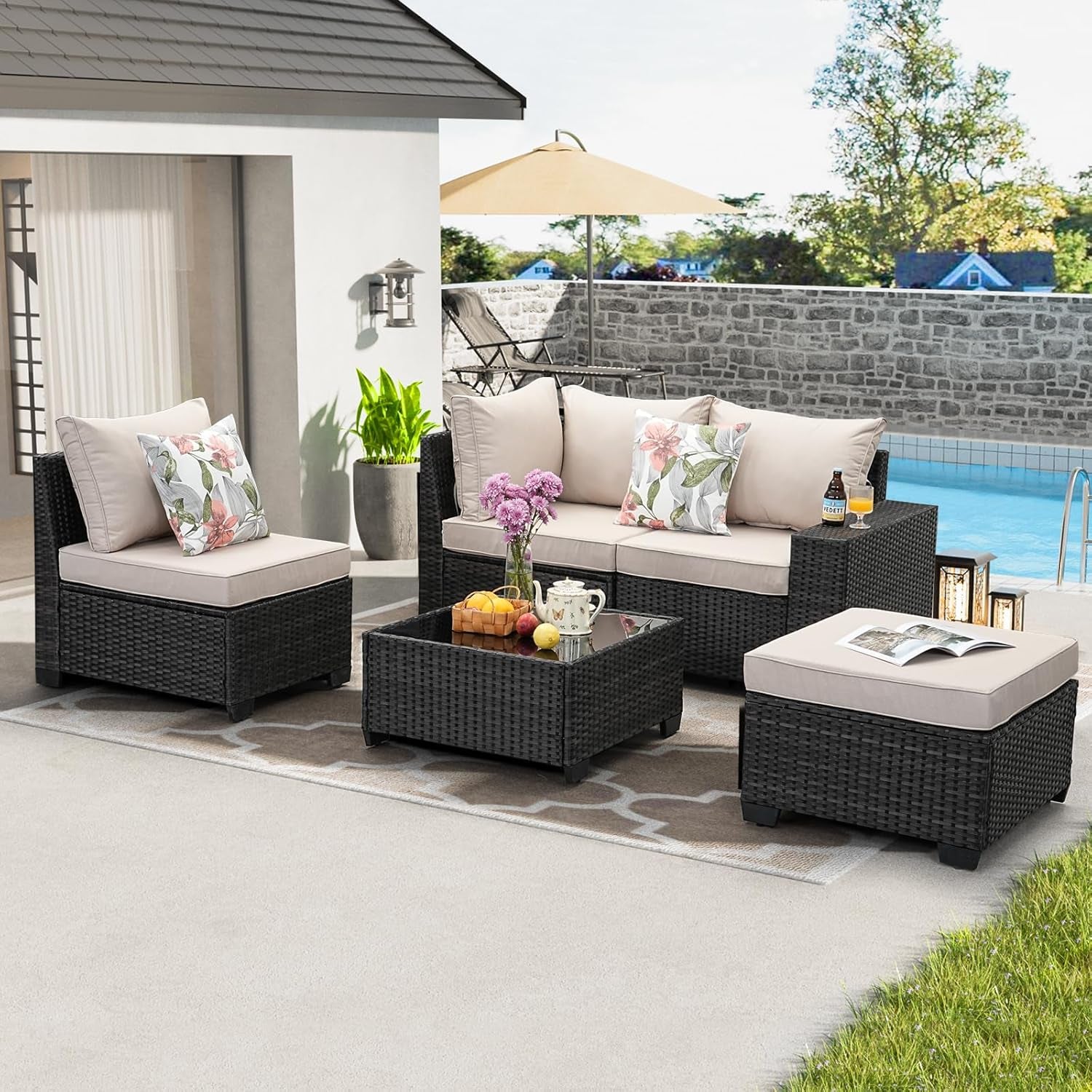Full outdoor setup with beige cushioned sofa, armless chair, ottoman and glass-top coffee table.