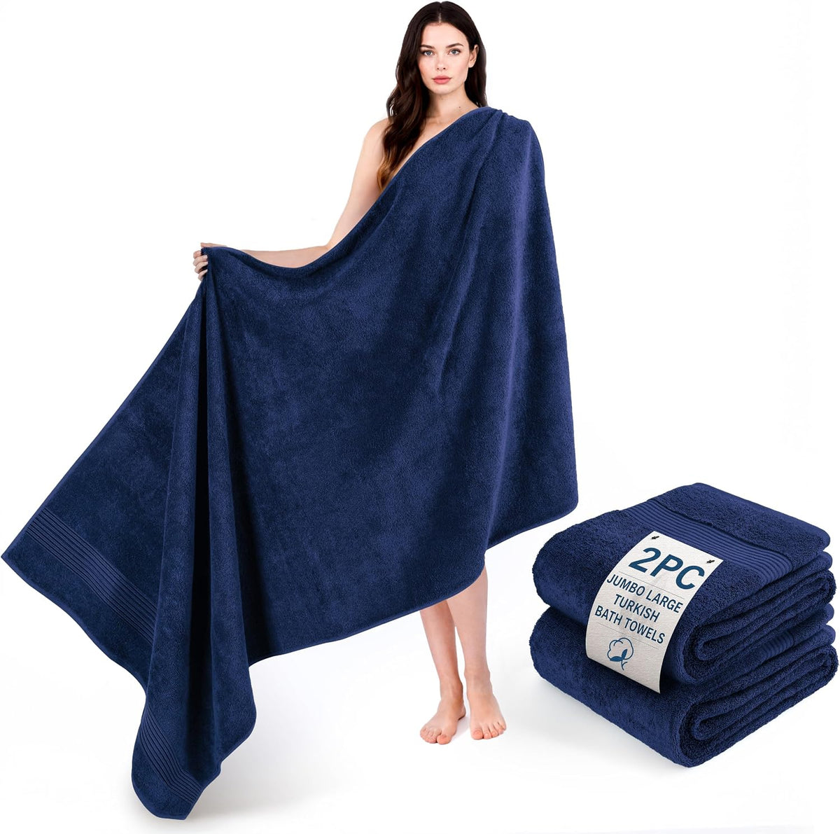 Woman wrapped in a large navy towel, with a folded navy towel stack at her feet