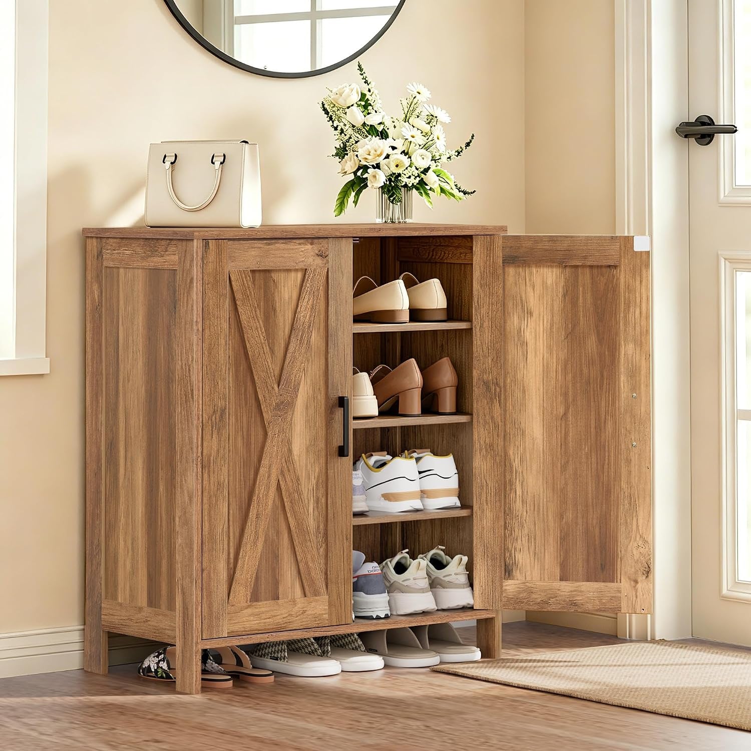 Warm wood-finish shoe cabinet in an entryway with both doors open revealing four shelves of shoes.