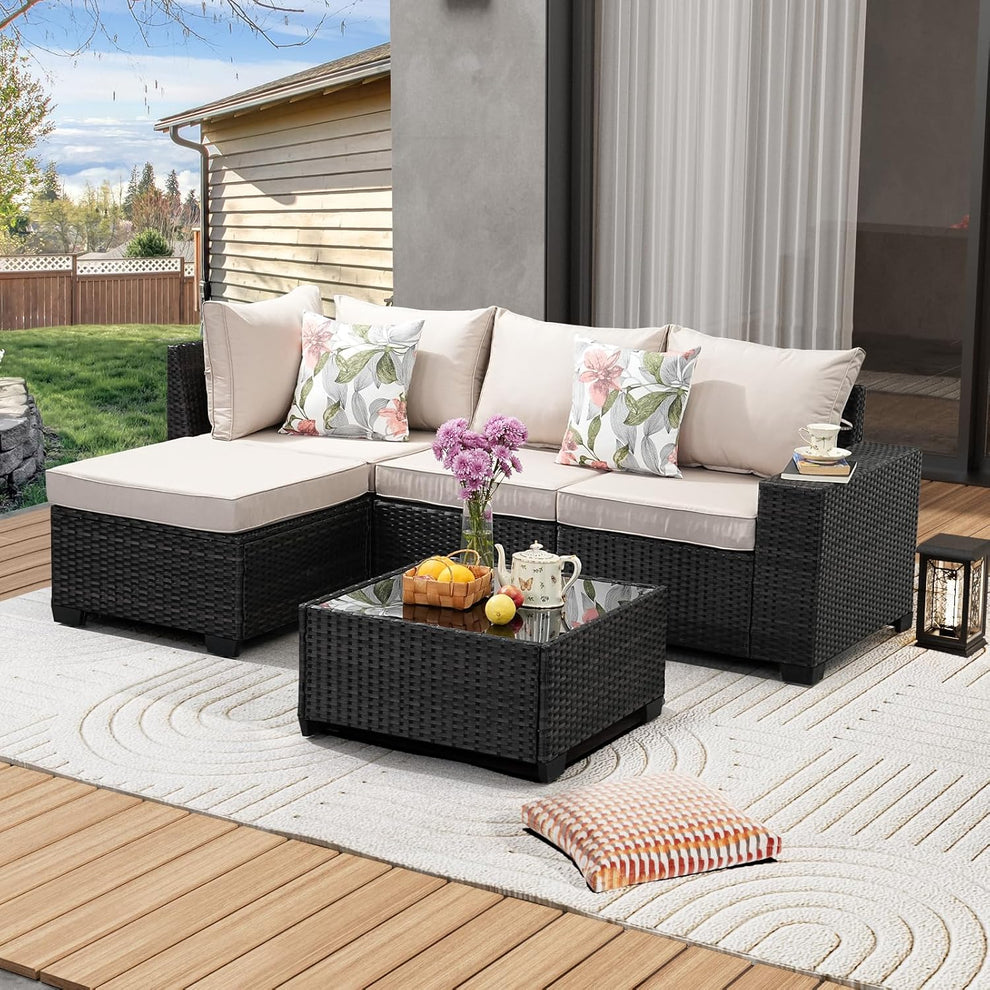 Beige 5-piece rattan patio sectional with glass coffee table shown on a deck, angled front view