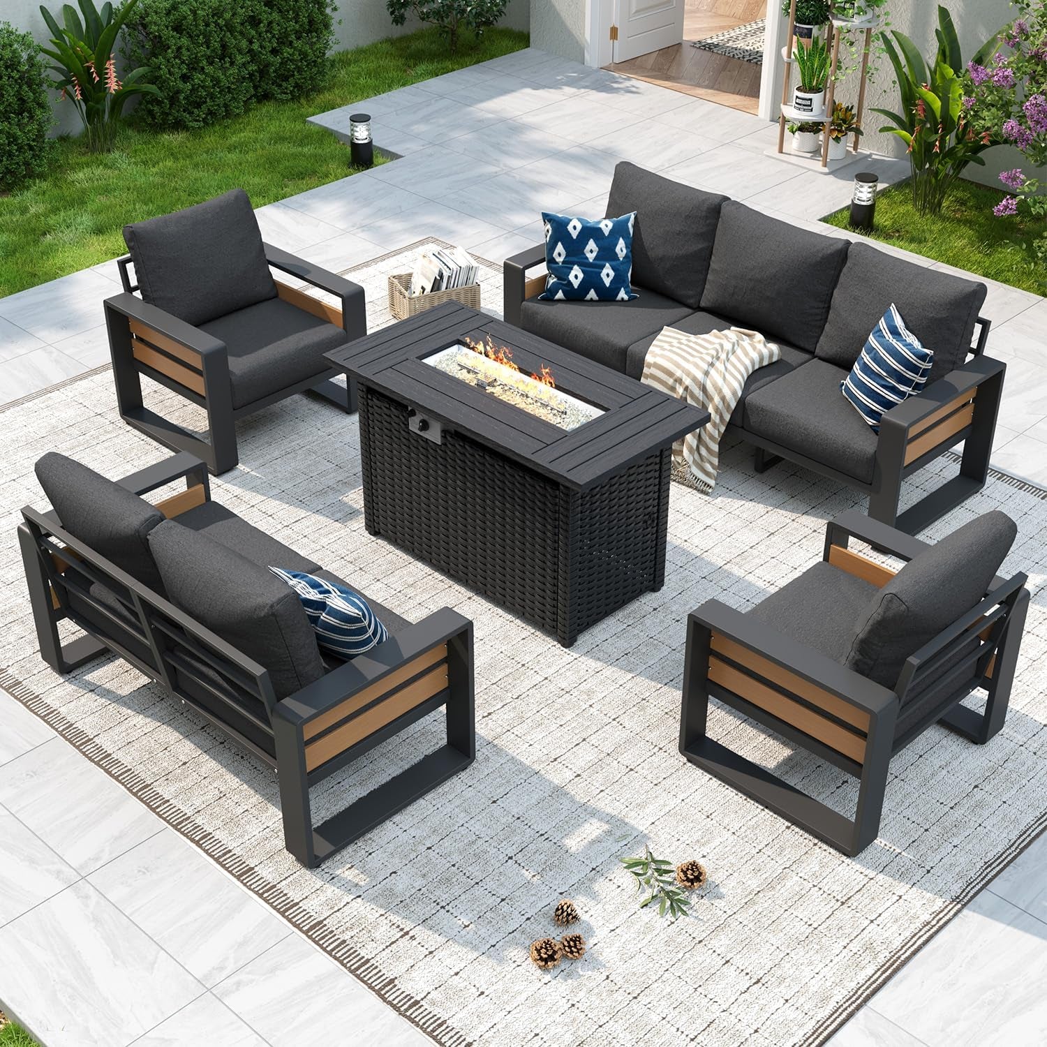 Outdoor patio arrangement with dark-gray cushioned sectional and chairs around a rectangular fire-pit table on a light woven