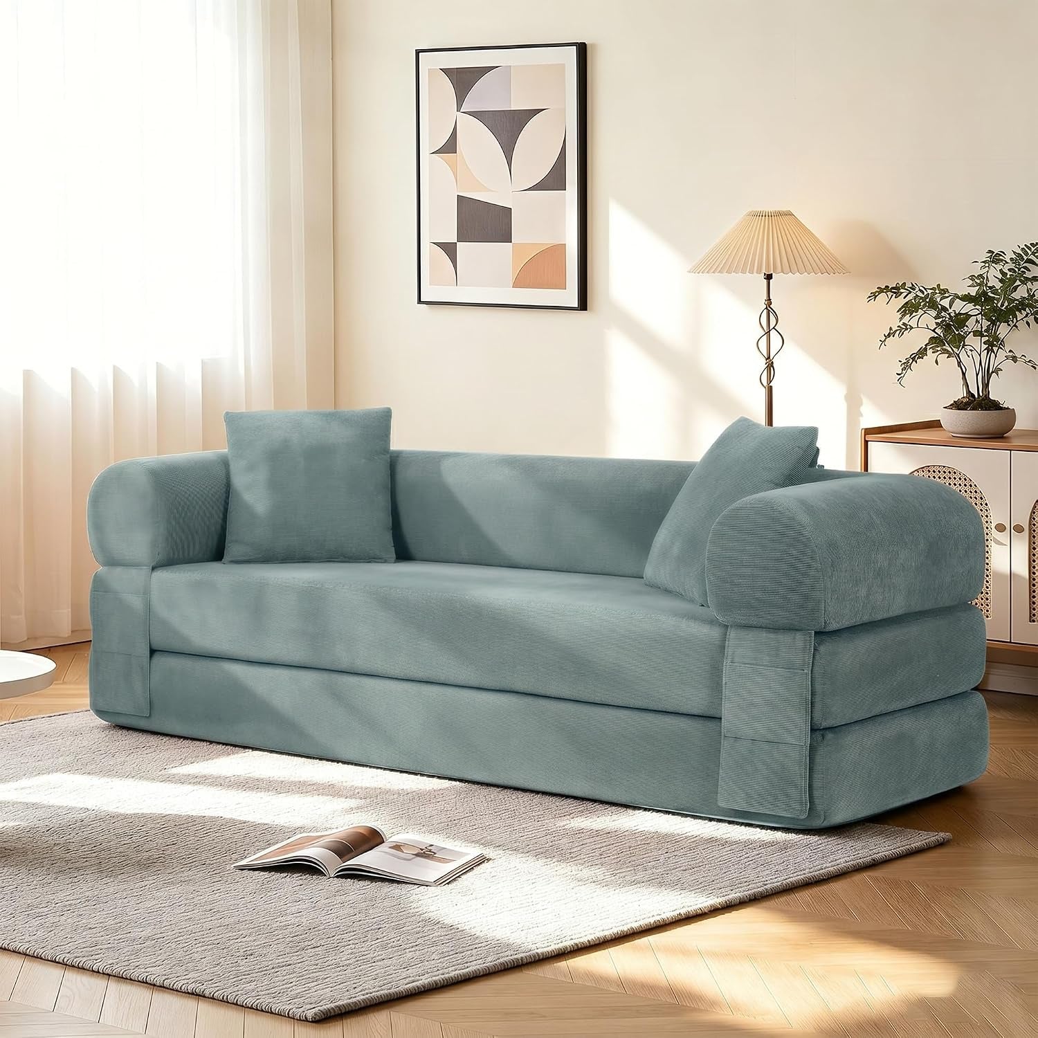 Light green corduroy convertible floor sofa arranged as a couch in a sunlit living room, angled front view