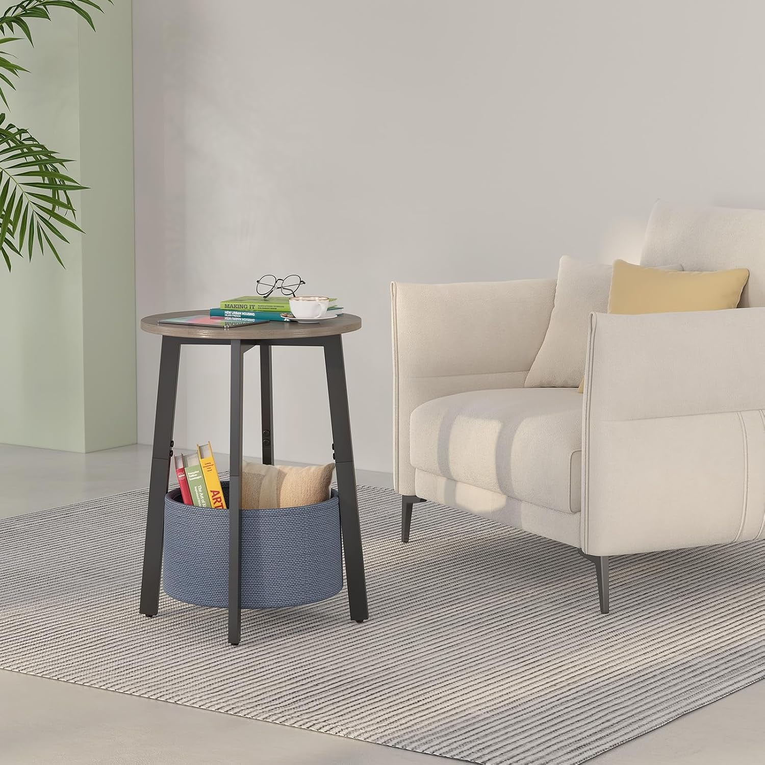 Table beside an armchair on a rug, wood top holding glasses and a cup, blue basket storing books and a pillow