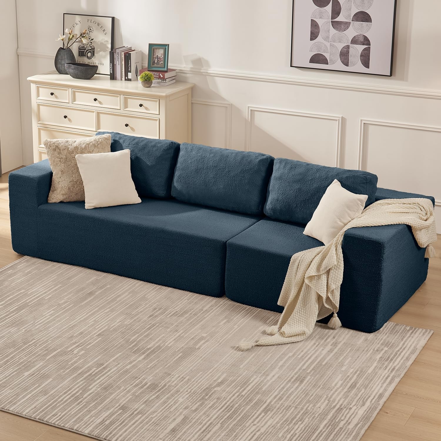 Angled view of a deep blue modular sofa without chaise, styled with pillows and a throw in a living room.