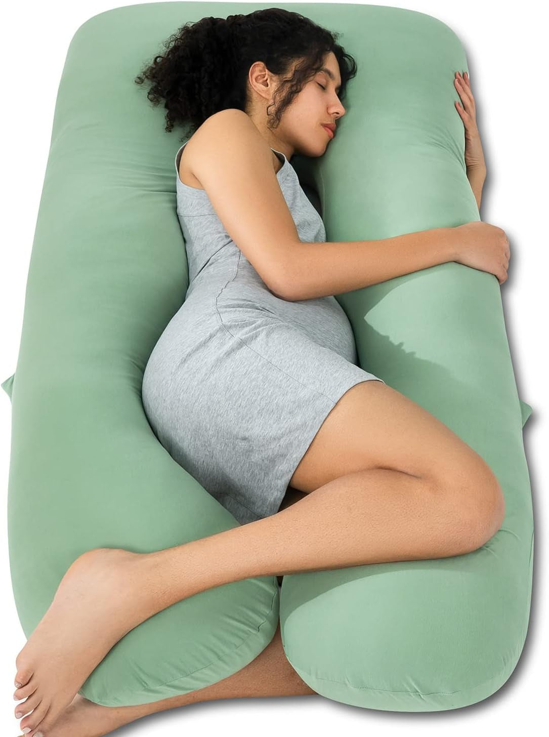 Top view of a pregnant woman sleeping sideways inside a mint green U-shaped maternity body pillow.