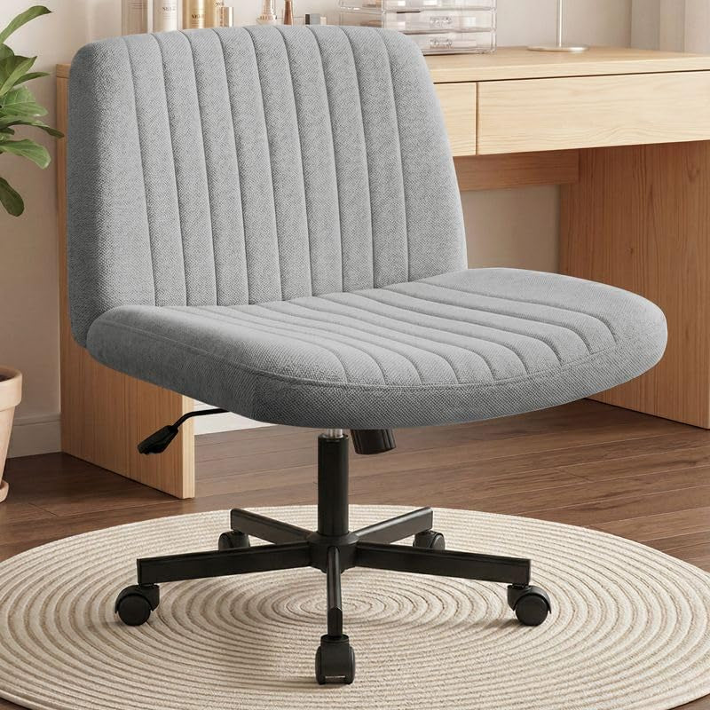 Light gray fabric swivel chair placed in front of a wood desk, showing cushioned seat, tufted back, and black casters.