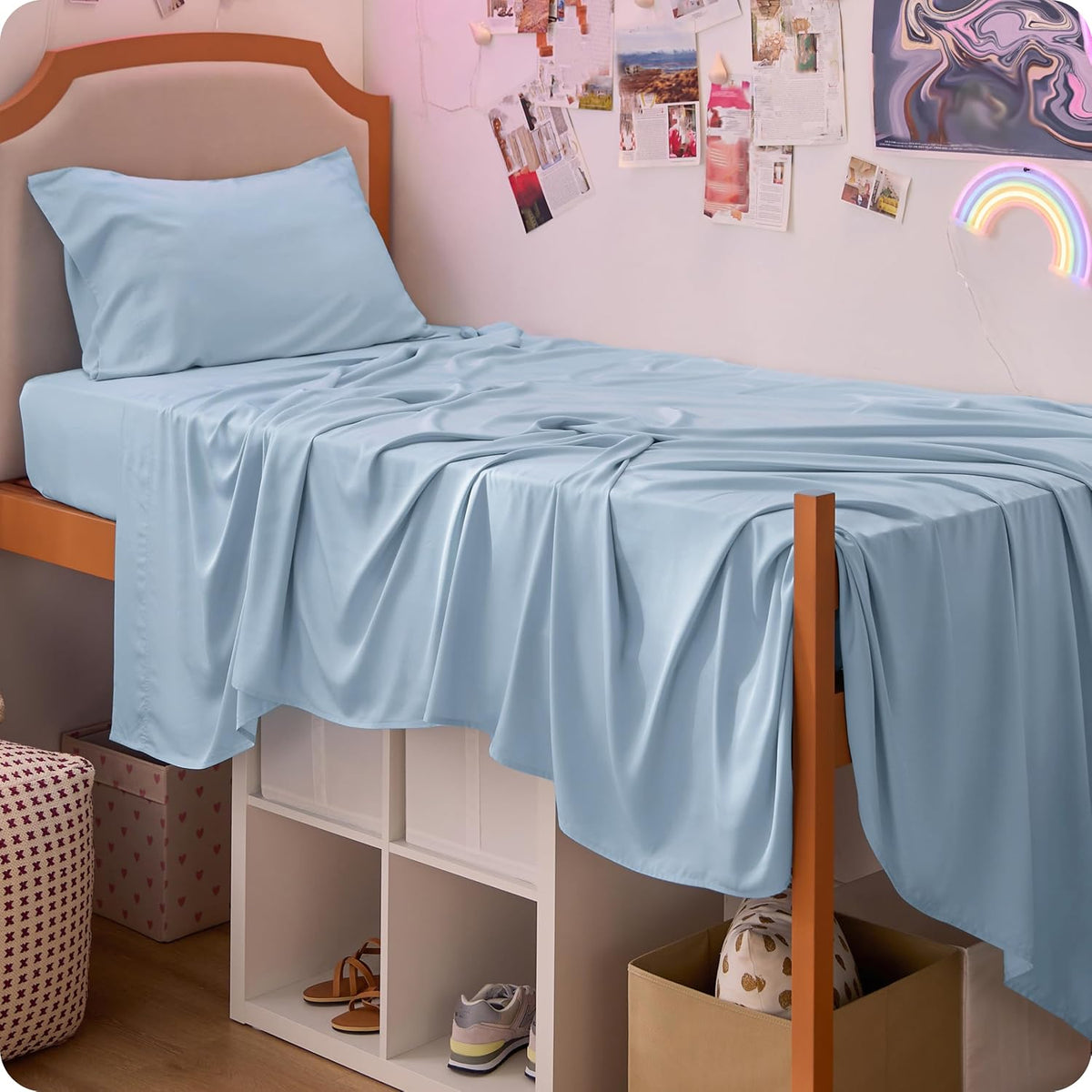 side view — light blue sheet draped over a raised bed frame with storage cubbies and shoes underneath.