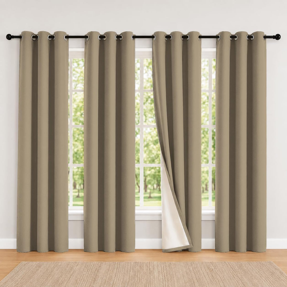 Large window with four warm taupe grommet curtains, center panel pulled back showing white backing.