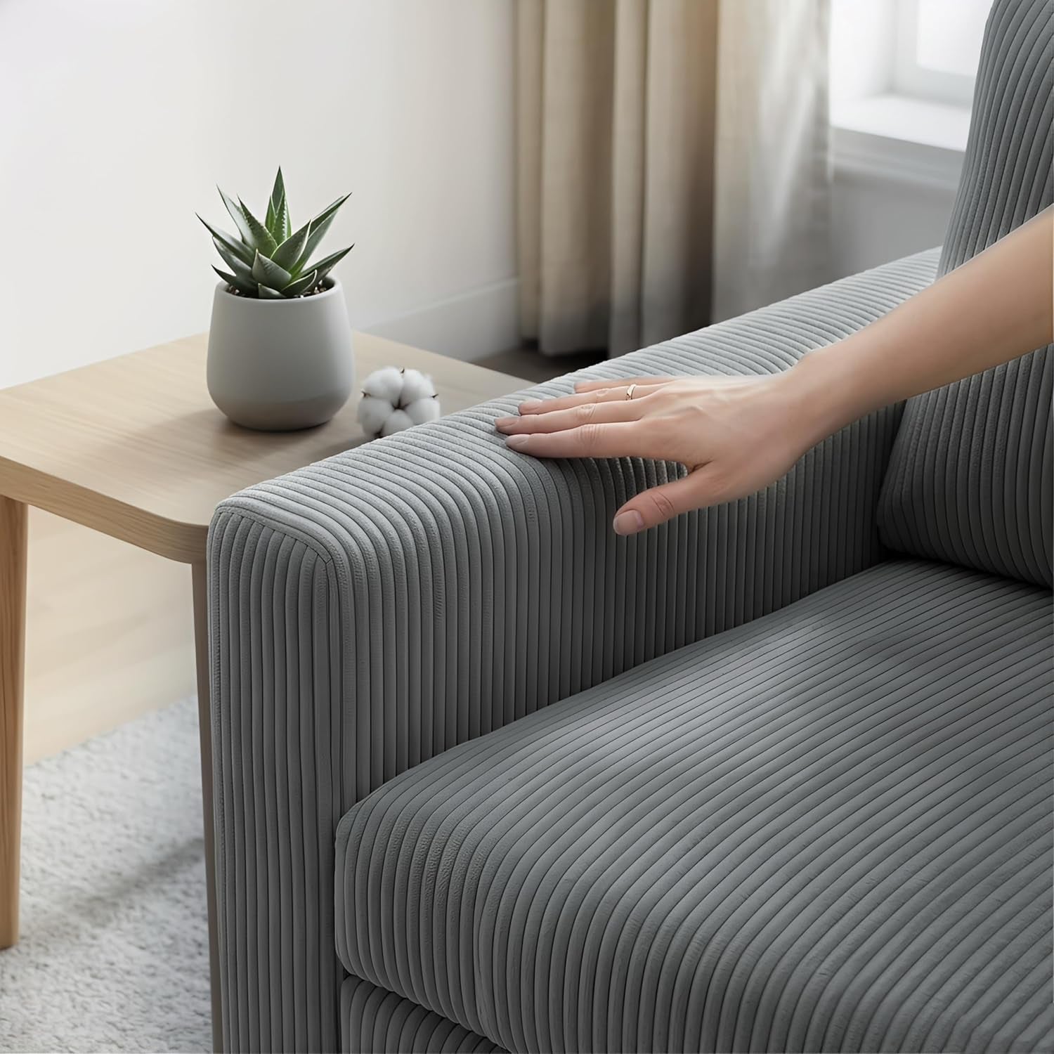Hand resting on the sofa arm to show soft gray corduroy ribbed upholstery texture.