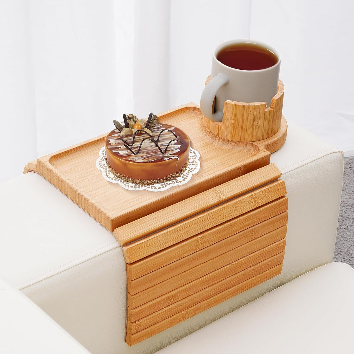 Bamboo couch arm tray on a white sofa arm with a rotating cup holder holding a mug and a dessert on the tray