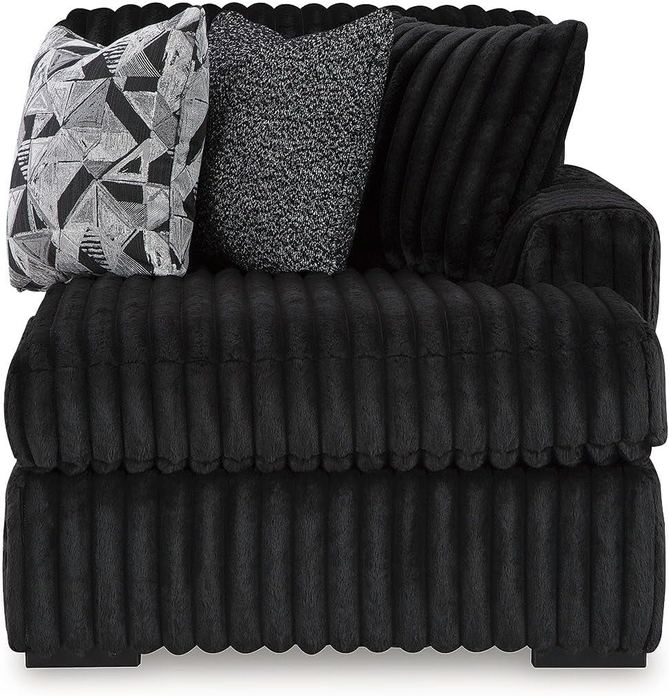 Close-up front view of one chaise section showing deep ribbed plush fabric, armrest, and three textured throw pillows.
