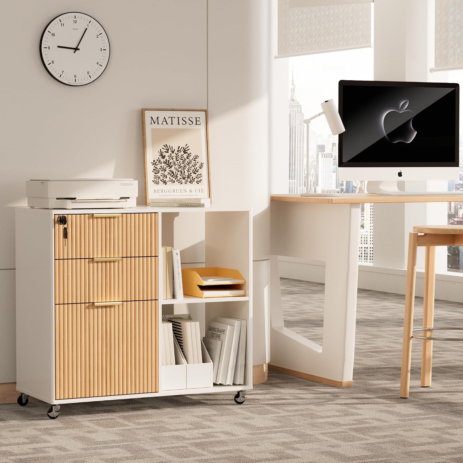 Low-angle office scene showing a white mobile file cabinet with light oak fluted drawer fronts beside a desk.