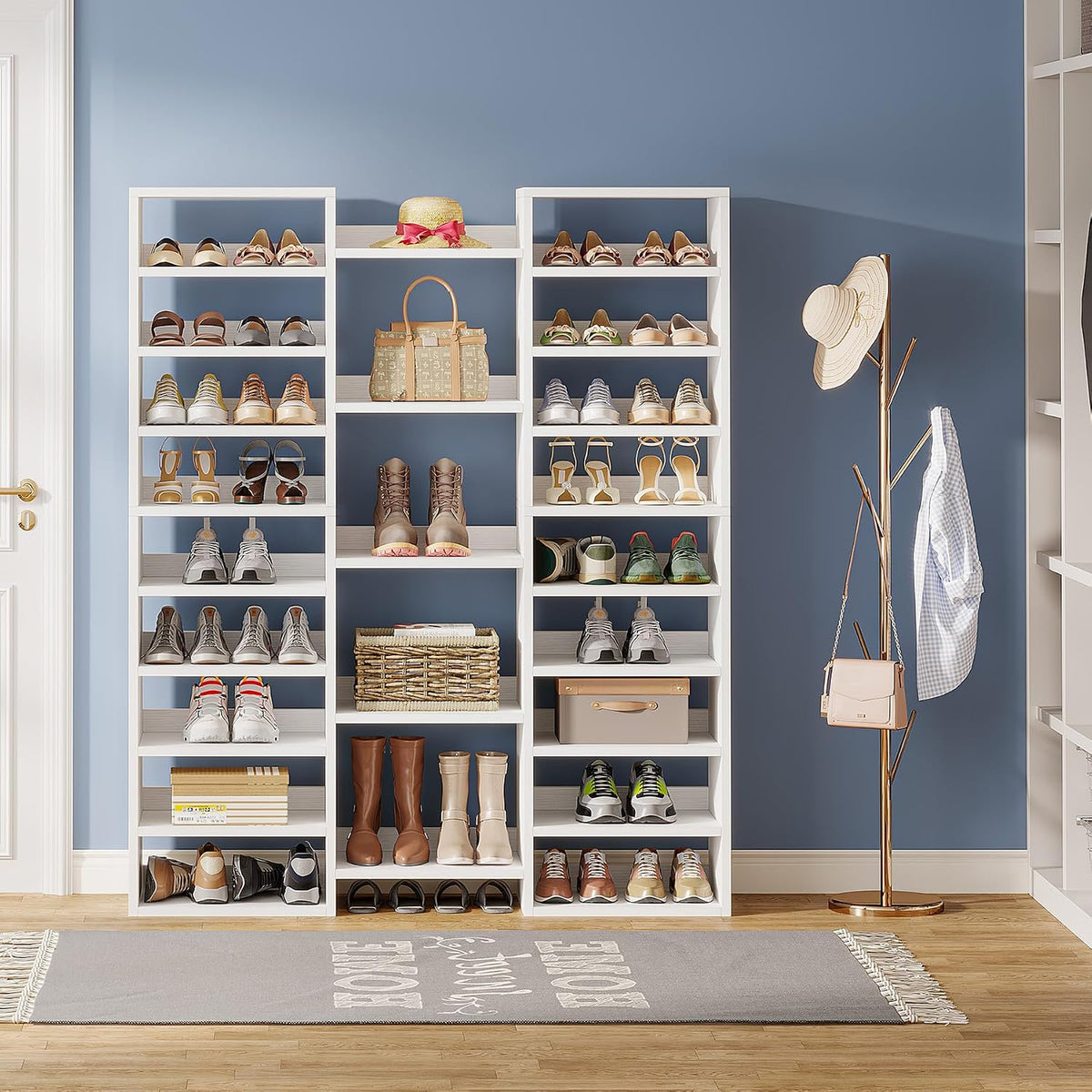 Three-column white shoe rack against a blue wall with shoes, a woven basket, and a gold hat-and-coat stand nearby.