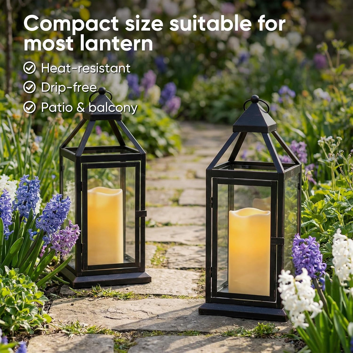 Ivory resin pillar candles shown inside black lanterns along a garden path amid flowers and greenery