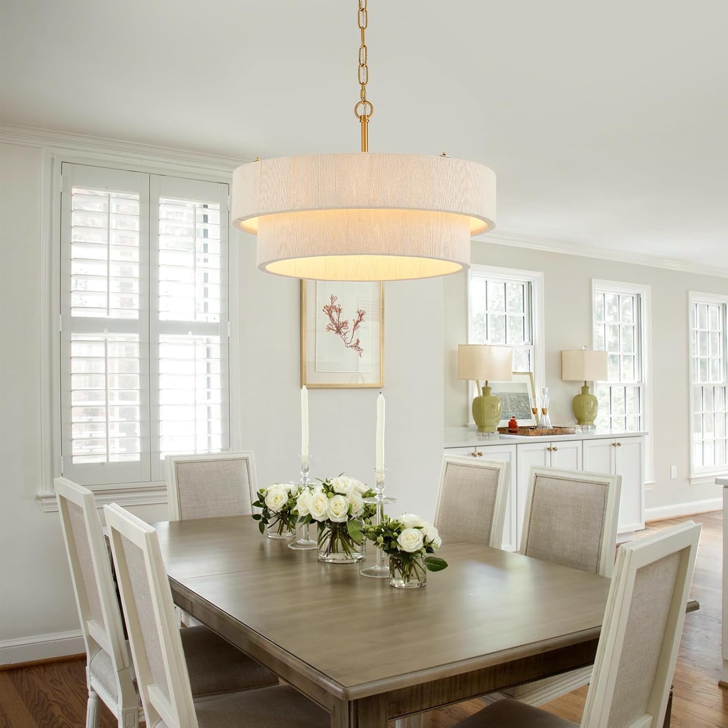 Cream two-ring rattan chandelier suspended above a dining table in a bright dining room setting