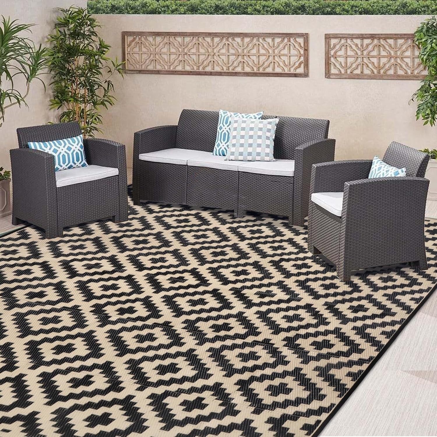 Patio set of sofa and two chairs arranged on a black-and-beige geometric outdoor rug.