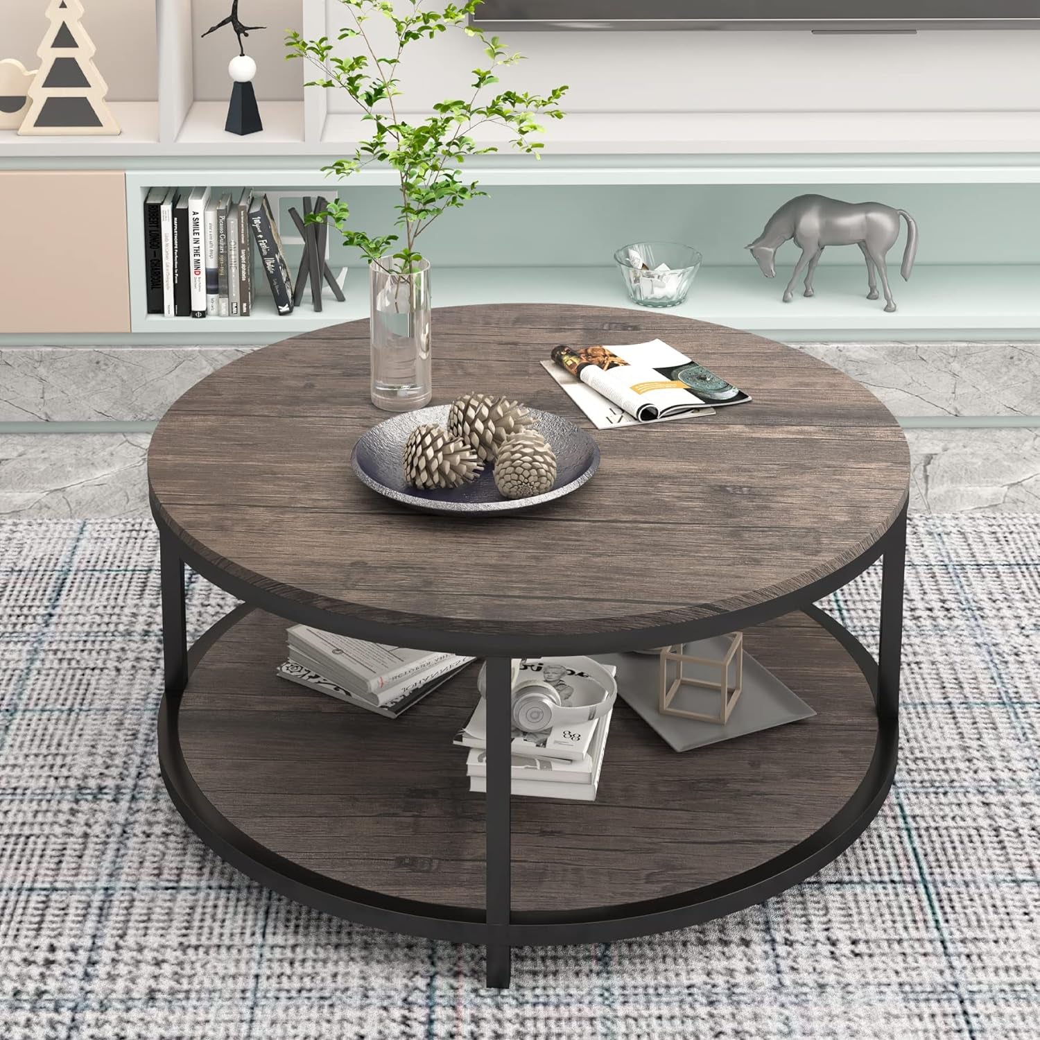 Top-down angled view of round two-tier table with books and decorative pieces on lower shelf