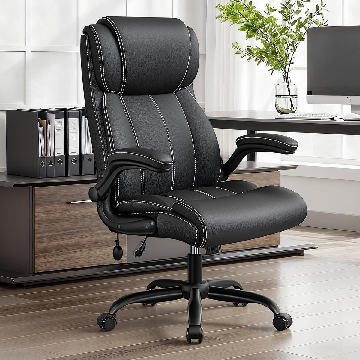 Black bonded PU high-back office chair angled front-right beside a desk in an office scene