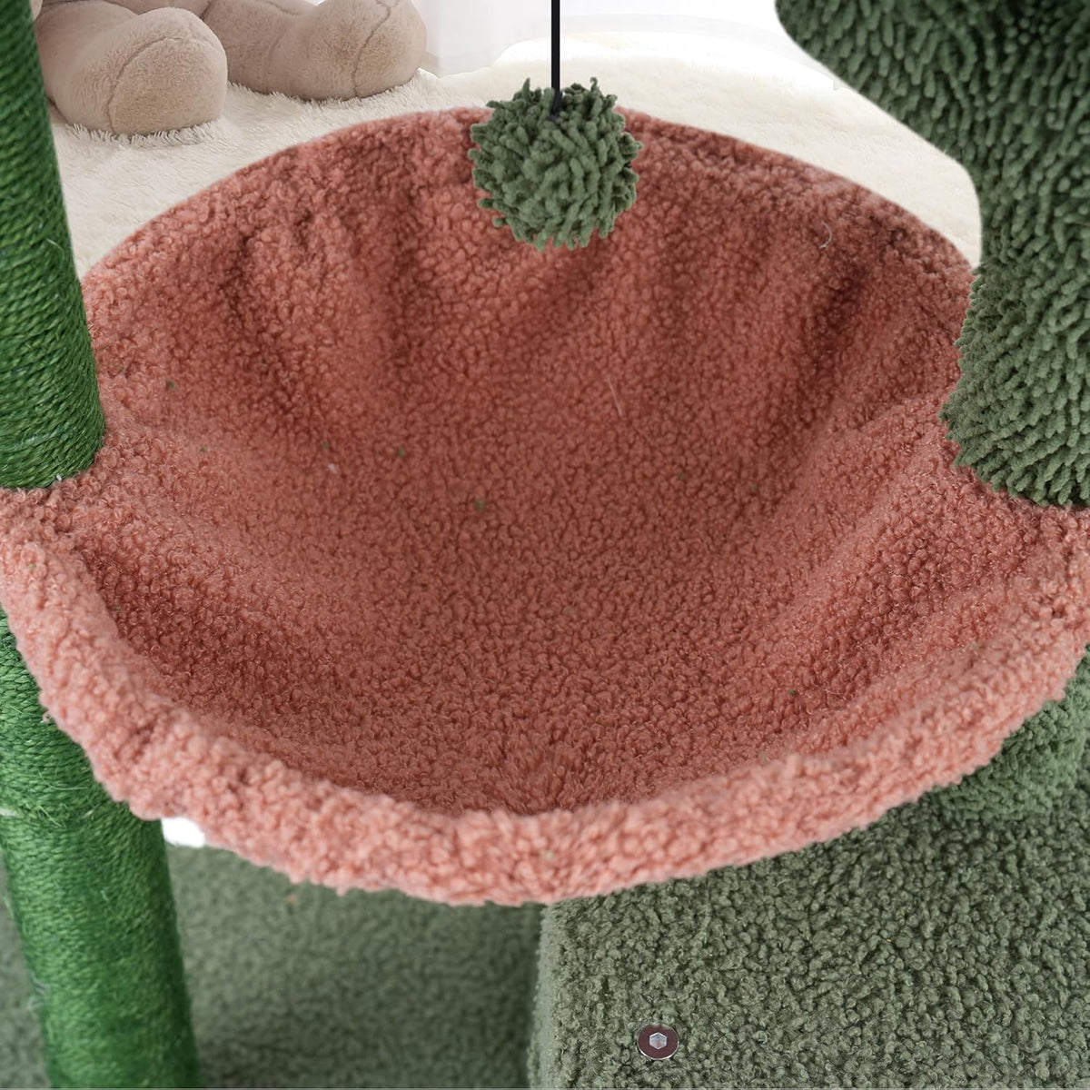 Interior view of the pink round hammock with hanging pompom toy and textured fabric