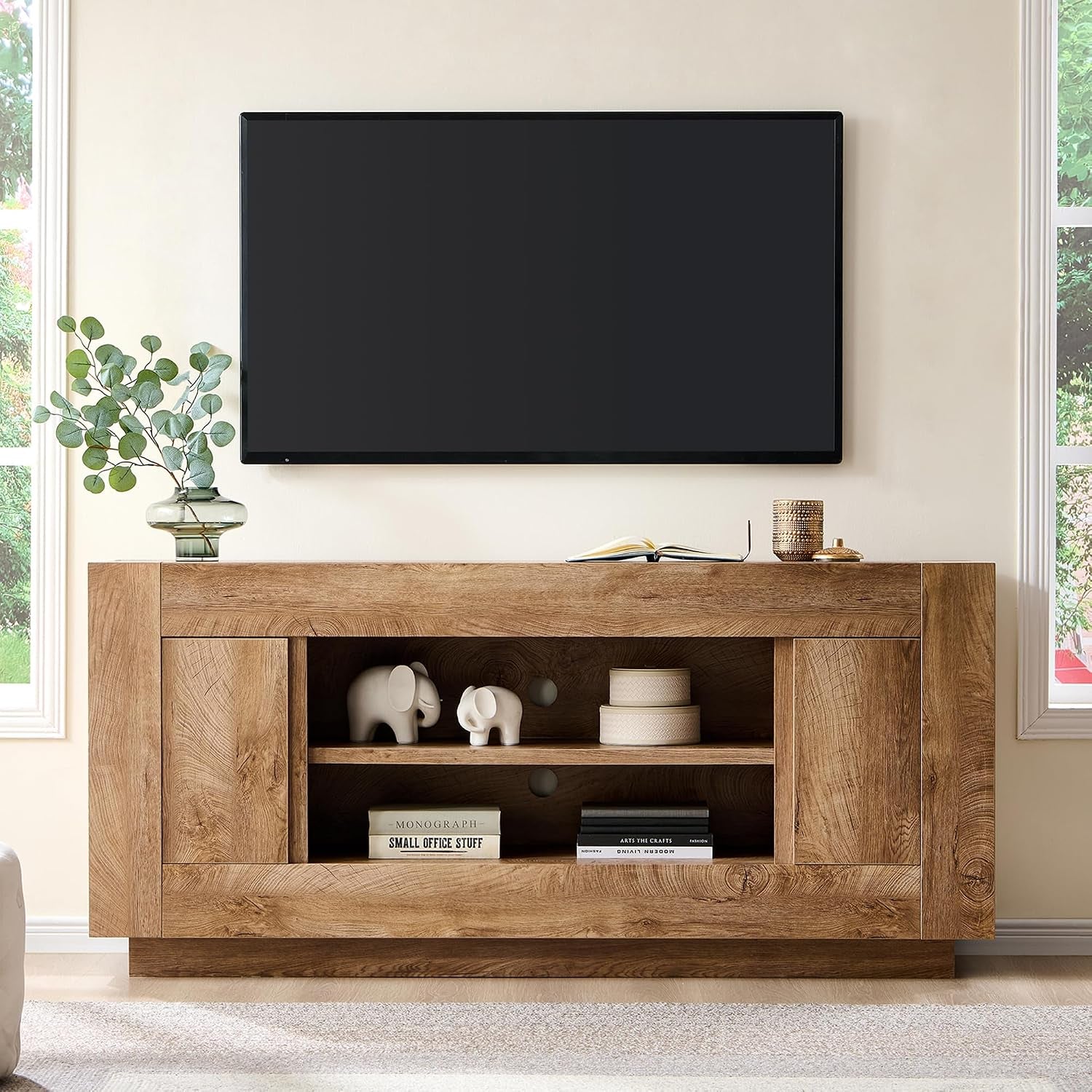 Light oak finish TV stand with open center shelving, decorative elephants and books, TV above