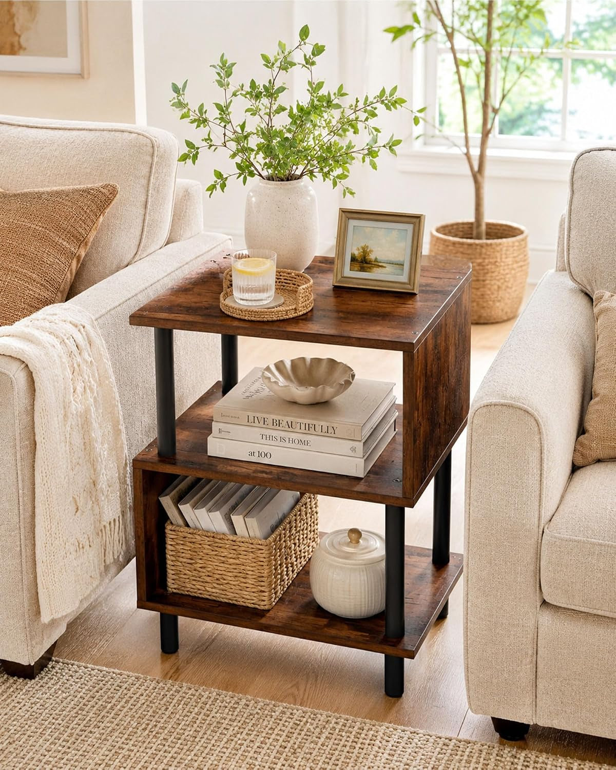 Rustic brown S-shaped side table staged between two sofas holding books and a basket, front view